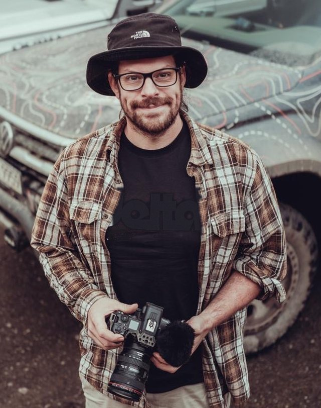 Alexander Mauz in a hat and glasses, holding a camera